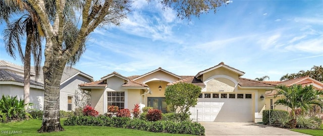 mediterranean / spanish-style house featuring a front yard, driveway, an attached garage, and stucco siding