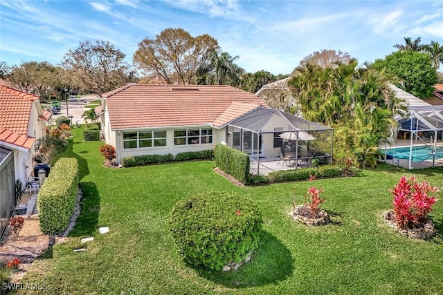 back of house featuring a tile roof, a lawn, a patio area, glass enclosure, and an outdoor pool