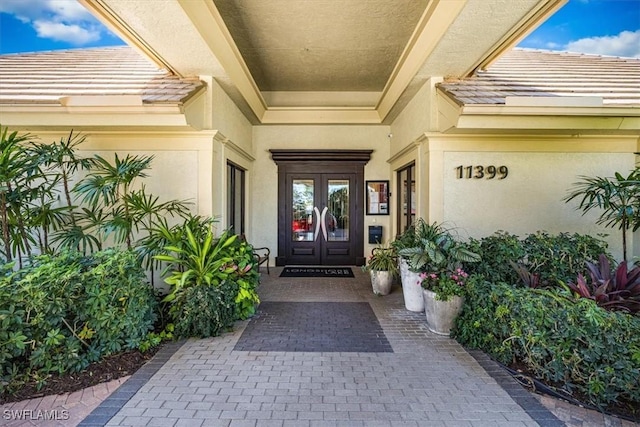 doorway to property featuring stucco siding, a tiled roof, and french doors