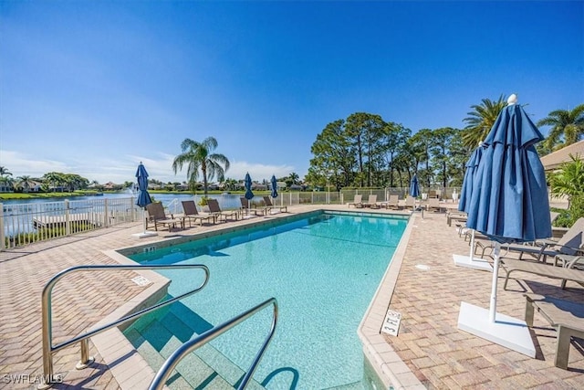 pool featuring a water view, a patio area, and fence