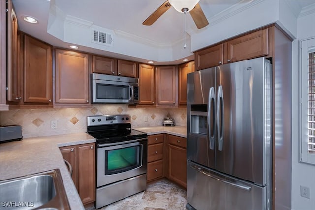 kitchen with appliances with stainless steel finishes, ornamental molding, light countertops, brown cabinets, and recessed lighting