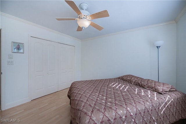 bedroom with wood finished floors, ornamental molding, a closet, a ceiling fan, and baseboards