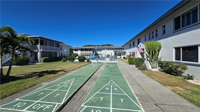 view of community featuring a lawn and shuffleboard