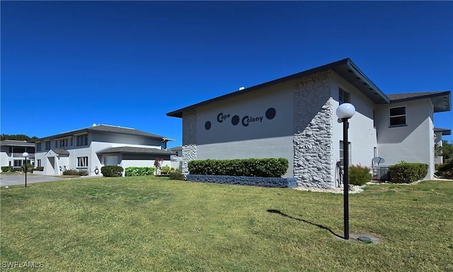view of side of home with stucco siding, a yard, and stone siding