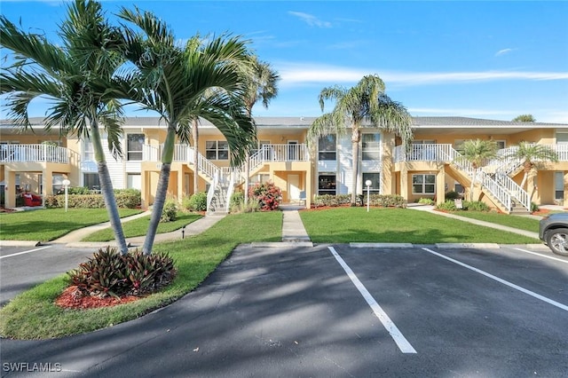 view of property featuring uncovered parking and stairs