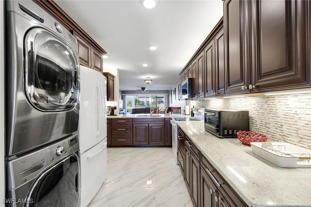 kitchen featuring white appliances, decorative backsplash, marble finish floor, stacked washing maching and dryer, and a sink