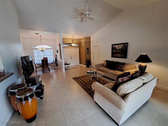 living room featuring light tile patterned floors, high vaulted ceiling, ceiling fan with notable chandelier, and baseboards