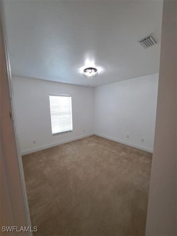 carpeted empty room featuring visible vents and baseboards