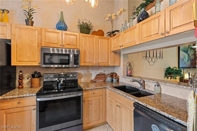 kitchen featuring stainless steel appliances, light brown cabinetry, and a sink