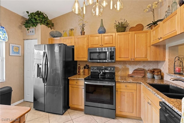 kitchen with light brown cabinetry, appliances with stainless steel finishes, a sink, and light stone countertops