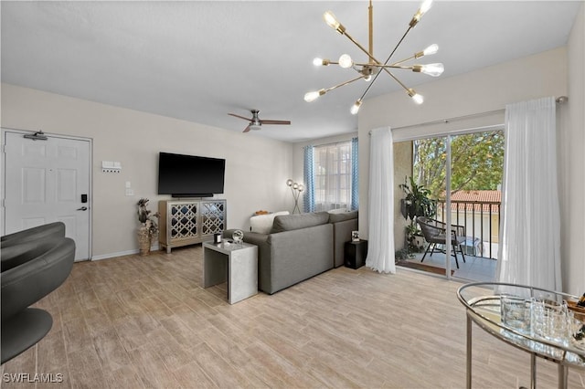 living room with ceiling fan with notable chandelier, baseboards, and light wood-style floors