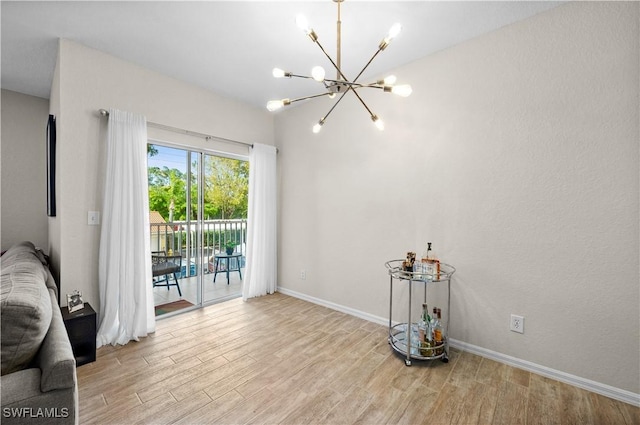 unfurnished room with baseboards, wood finished floors, and an inviting chandelier