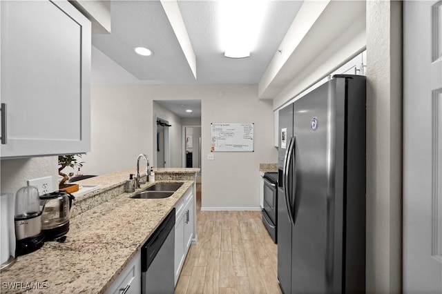 kitchen featuring light wood finished floors, black range with electric stovetop, a sink, refrigerator with ice dispenser, and stainless steel dishwasher