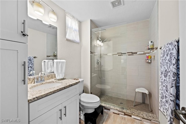 full bath with toilet, a stall shower, vanity, and visible vents