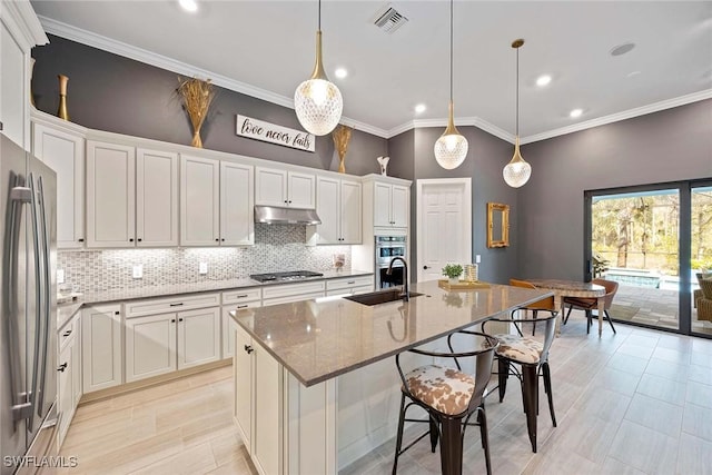 kitchen featuring visible vents, appliances with stainless steel finishes, a sink, under cabinet range hood, and backsplash