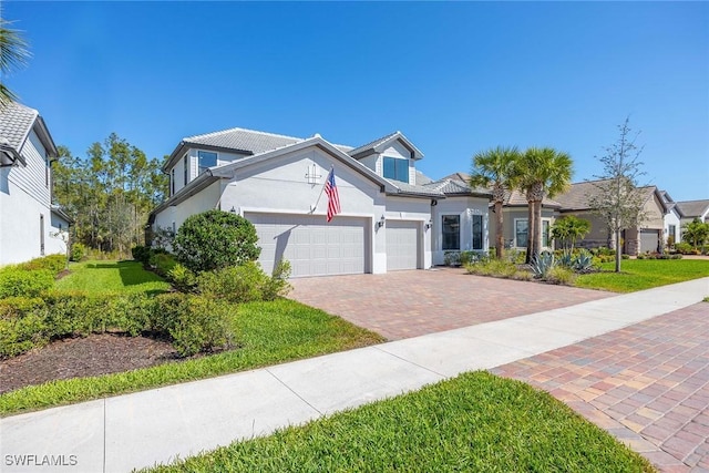 view of front of property featuring an attached garage, a front yard, decorative driveway, and stucco siding