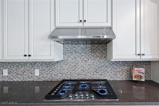 kitchen featuring white cabinets, stainless steel gas cooktop, under cabinet range hood, and decorative backsplash