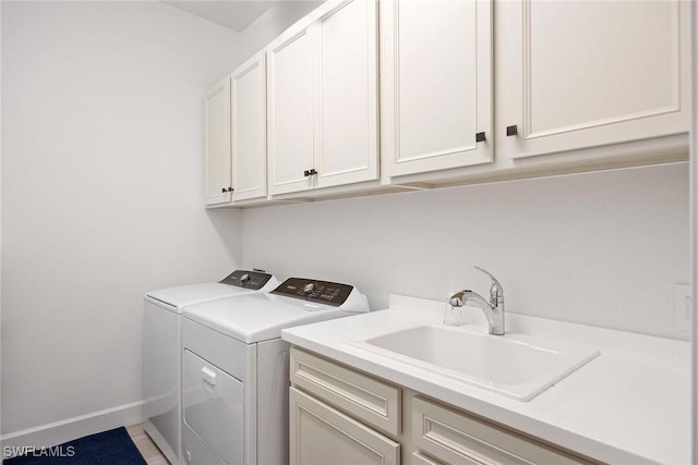 laundry area featuring a sink, washing machine and clothes dryer, cabinet space, and baseboards