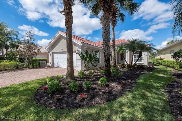 mediterranean / spanish-style home with a garage, a tiled roof, decorative driveway, stucco siding, and a front lawn