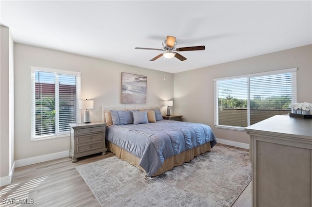 bedroom with ceiling fan, light wood-style flooring, and baseboards