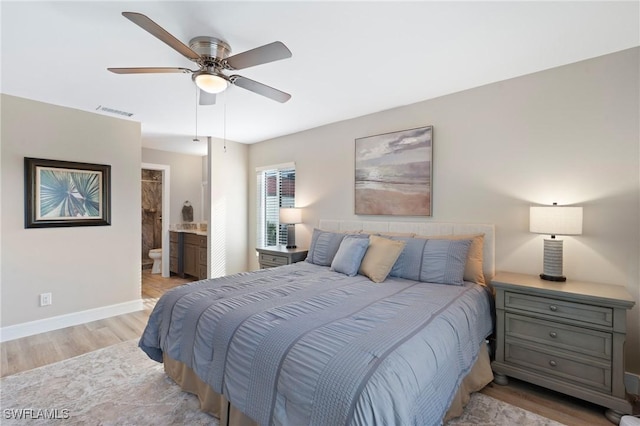 bedroom with ensuite bathroom, ceiling fan, wood finished floors, visible vents, and baseboards