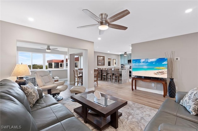 living room with recessed lighting, baseboards, and light wood finished floors