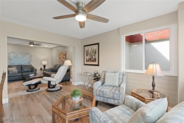 living room featuring wood finished floors, a ceiling fan, and baseboards