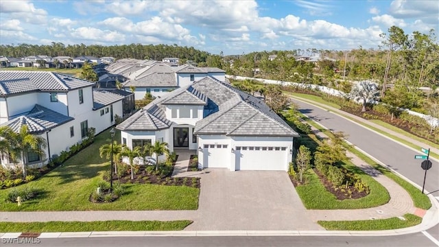 view of front of property featuring decorative driveway, stucco siding, a front yard, a garage, and a residential view