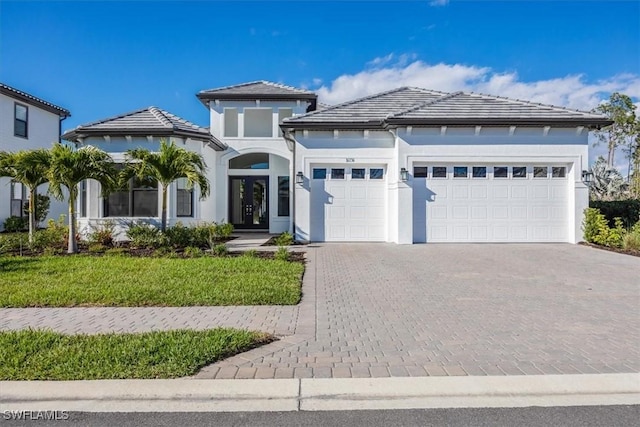 prairie-style house with a garage, a tiled roof, a front lawn, and decorative driveway