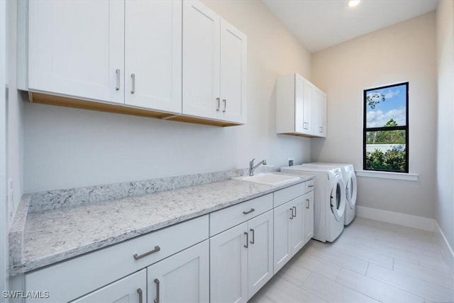 washroom featuring washer and dryer, cabinet space, a sink, and baseboards