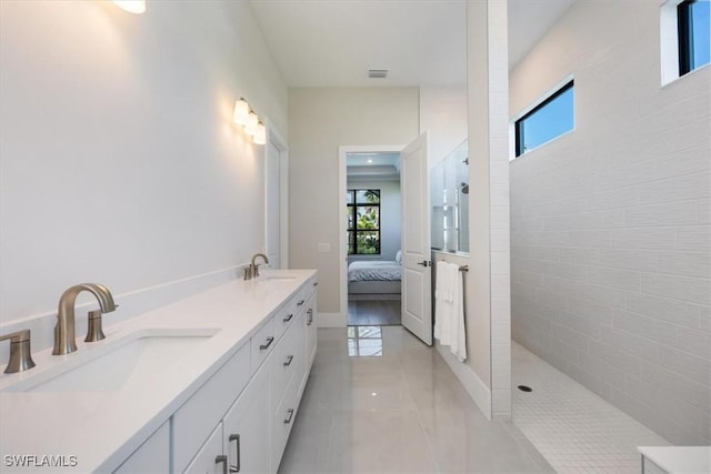 bathroom featuring tile patterned flooring, a walk in shower, a sink, and ensuite bathroom