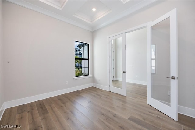 empty room featuring coffered ceiling, wood finished floors, baseboards, ornamental molding, and french doors