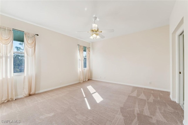 spare room featuring light carpet, ceiling fan, and baseboards