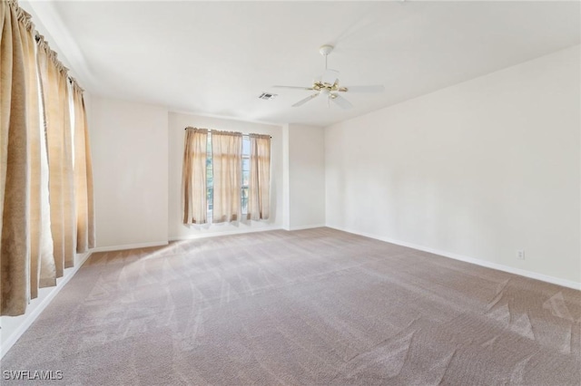 unfurnished room featuring carpet floors, visible vents, baseboards, and a ceiling fan