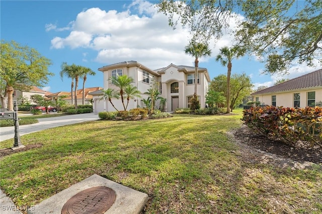 mediterranean / spanish house featuring concrete driveway, an attached garage, a front lawn, and stucco siding