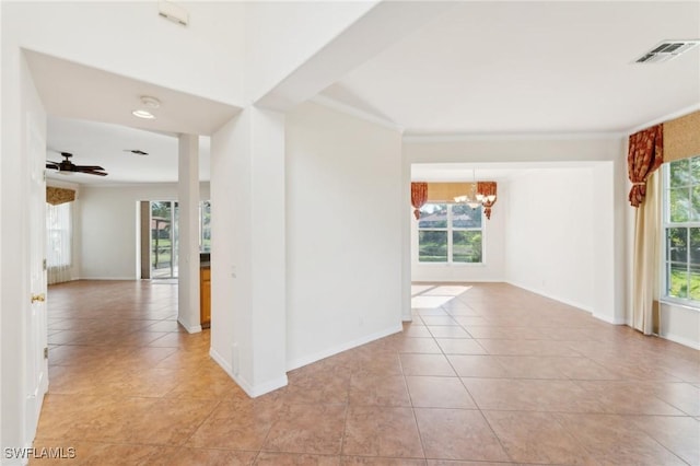 empty room with light tile patterned flooring, ceiling fan with notable chandelier, visible vents, baseboards, and crown molding