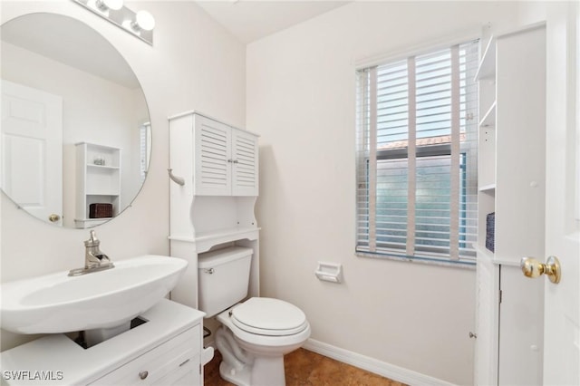 half bath featuring toilet, baseboards, and vanity