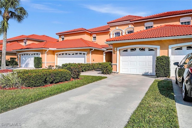 mediterranean / spanish-style home with a garage, driveway, a tiled roof, and stucco siding