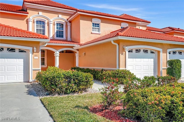 mediterranean / spanish home with a tiled roof, an attached garage, and stucco siding