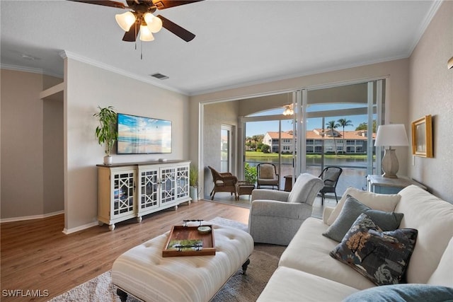 living area with crown molding, visible vents, a ceiling fan, wood finished floors, and baseboards