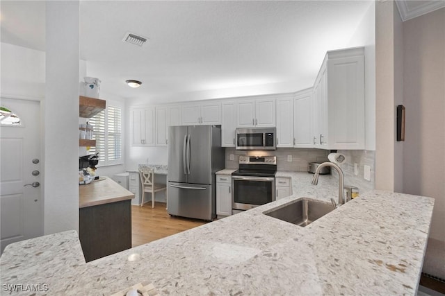 kitchen with visible vents, a sink, stainless steel appliances, light wood-type flooring, and backsplash