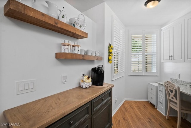 interior space featuring baseboards, light wood finished floors, and open shelves