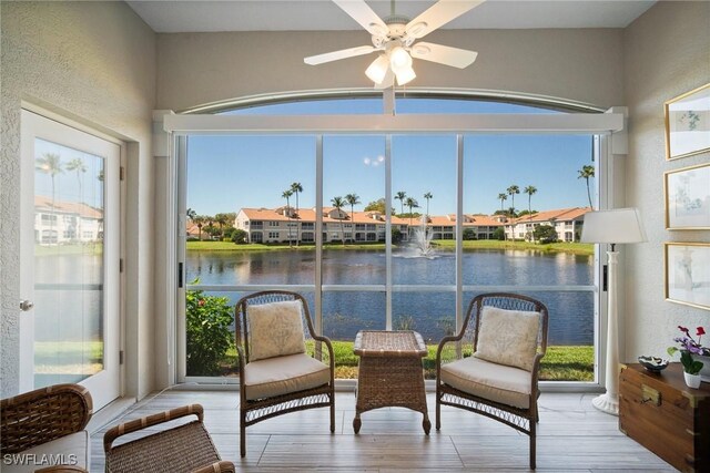 sunroom featuring a water view and a ceiling fan