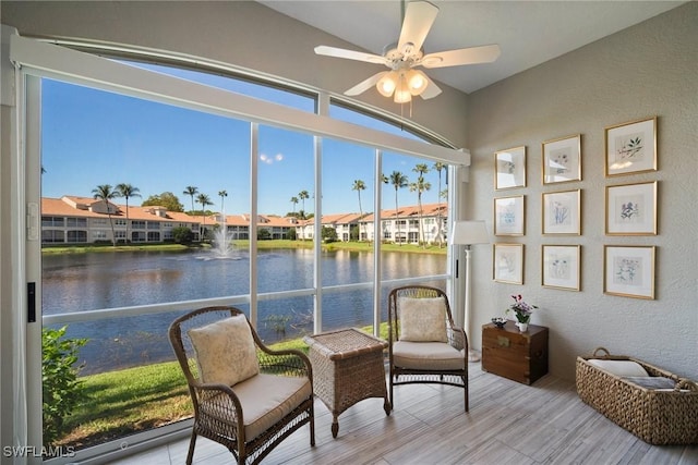 sunroom / solarium with a water view, a residential view, and a ceiling fan