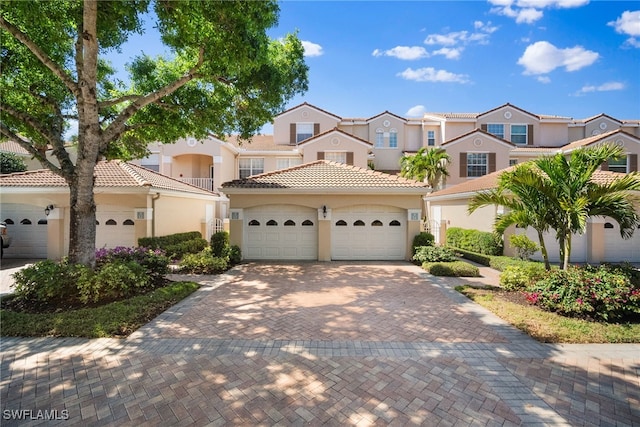 mediterranean / spanish house with a residential view, decorative driveway, a tiled roof, and stucco siding