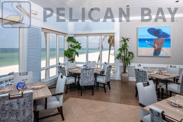 tiled dining room with a water view and a beach view