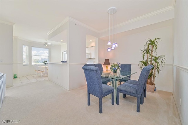 dining area featuring light colored carpet, crown molding, baseboards, and ceiling fan