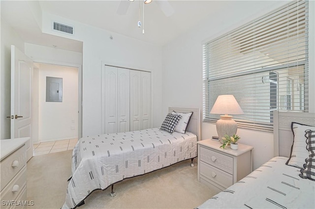 bedroom featuring electric panel, visible vents, light colored carpet, ceiling fan, and a closet