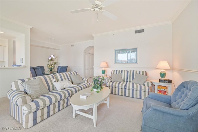 living room featuring carpet floors, arched walkways, visible vents, ornamental molding, and a ceiling fan