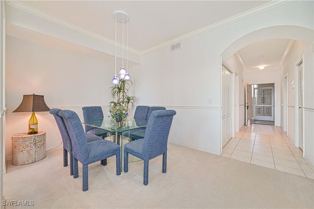 carpeted dining room featuring visible vents, arched walkways, crown molding, and tile patterned floors